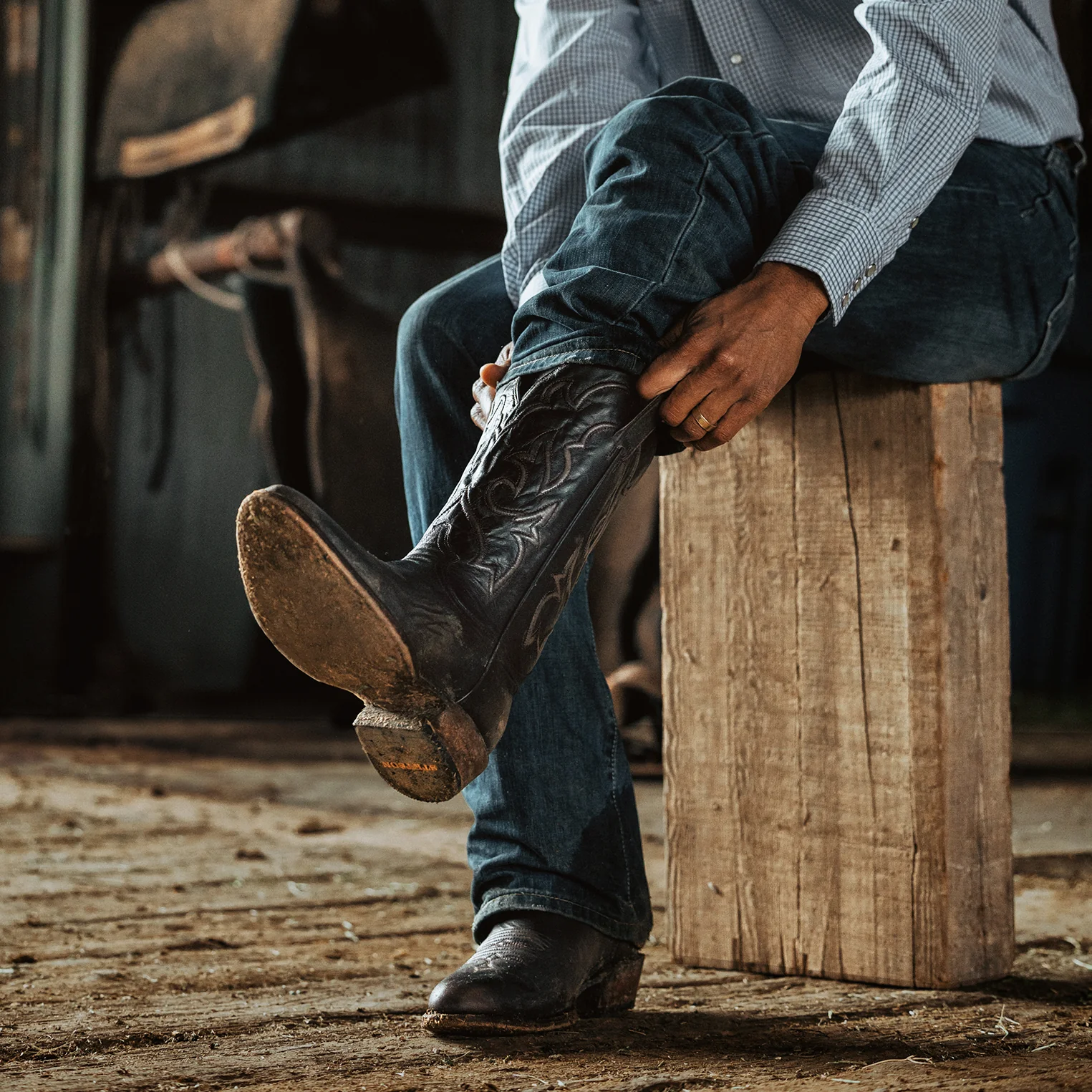 homme assis qui met des bottes santiag